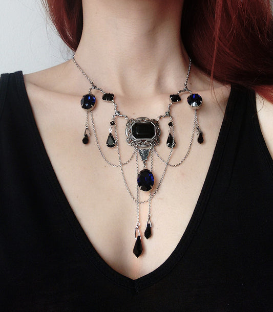 Gothic necklace with black and blue Swarovski crystals worn with black top, featuring ornate silver setting and layered chains. Ideal for gothic fashion.