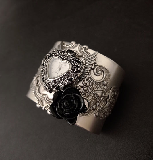 Gothic silver cuff bracelet with flourishes, wings, a black rose and a heart shaped watch face.