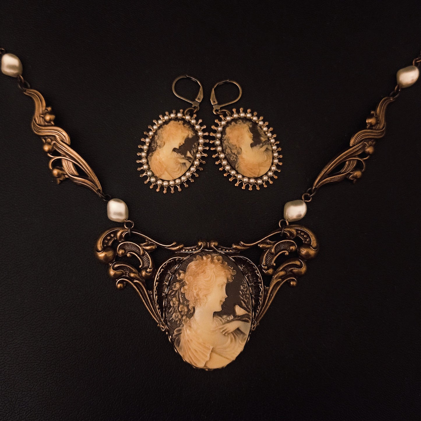 A Victorian jewelry set of bronze-toned necklace and matching earrings featuring ivory cameos of a woman me, framed with ornate scrollwork and pearl accents. Gothic Victorian jewelry, vintage jewelry 