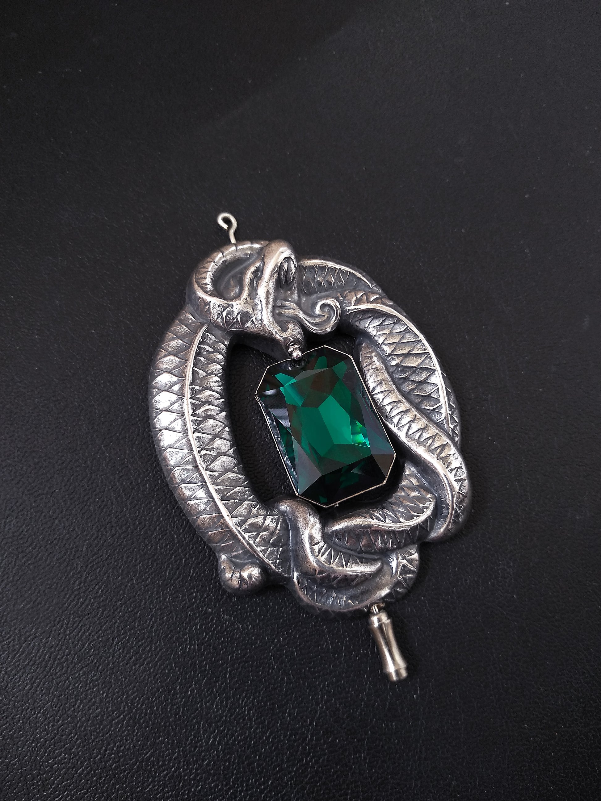 Silver Gothic brooch pin shaped as a large coiled snake with amazing details wrapped around a large Emerald Austrian crystal jewel in octagon shape.